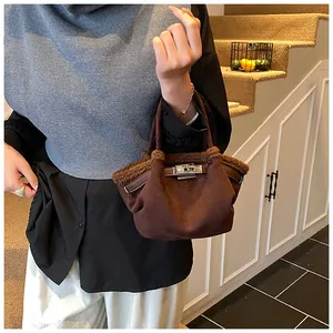 Detail of dark brown suede bucket bag with faux fur trim and silver metal twist lock clasp