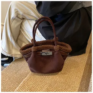 Detail of dark brown faux suede bucket bag with shearling trim and silver metal lock