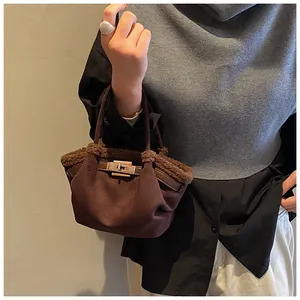 Detail of plush brown shoulder bag with dark leather handle and silver metal buckle