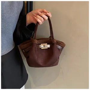 Detail of brown suede bucket bag with shearling trim and golden twist lock closure
