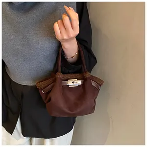 Detail of a dark brown suede bucket bag with shearling trim and metal turn-lock closure
