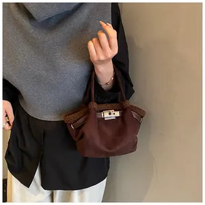 Close-up of dark coffee suede bucket bag with plush shearling trim and silver metal lock