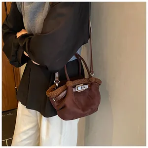Detail of dark brown suede bucket bag with plush shearling trim and metal lock closure