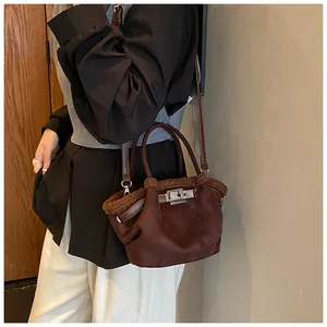 Detail of suede bucket bag with faux shearling trim and silver metal twist lock