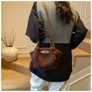 Detail of a brown suede bucket bag with faux fur trim and silver turn-lock closure