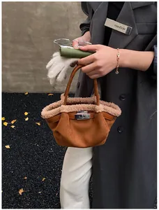 Detailed view of a brown suede bucket bag with shearling trim and silver turn-lock closure