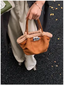 Close-up of brown suede bucket bag with fluffy faux shearling trim and metal twist lock
