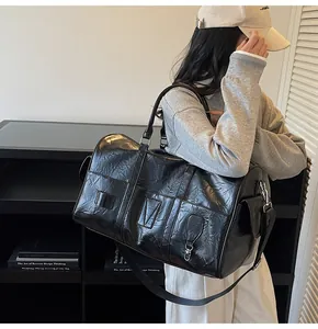 Dettaglio della borsa tote nera lucida con tracolla regolabile e finitura in pelle