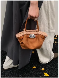 Macro detail of brown suede bucket bag featuring cream faux shearling trim and metal clasp