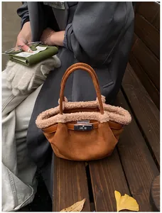 Close-up of caramel suede bucket bag with beige faux fur trim and silver metal buckle