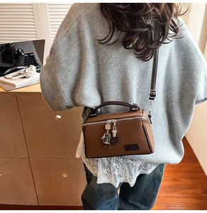 Vista posteriore di una modella con la borsa a tracolla in pelle marrone in un ambiente interno accogliente