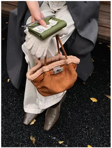 Detail of brown suede bucket bag with beige faux fur trim and silver turn-lock closure