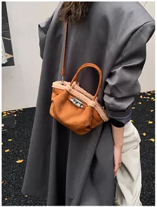 Detail of caramel brown suede bucket bag with faux fur trim and silver turn-lock closure
