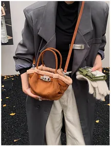Detail of brown suede bucket bag with beige shearling trim and silver metal twist lock