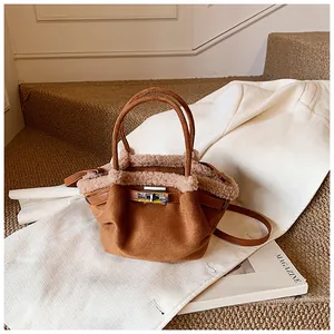 Detail of caramel brown suede bucket bag with plush faux shearling trim and metal clasp