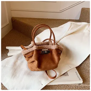 Detail of brown suede bucket bag featuring beige faux fur trim and silver turn-lock buckle