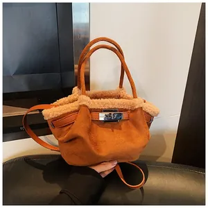 Detail of caramel suede bucket bag with faux fur trim and silver turn-lock closure