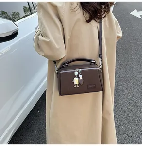 Dettaglio ravvicinato della borsa a tracolla marrone scuro con ciondoli in metallo e logo