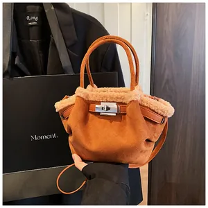 Detail of brown suede bucket bag with beige faux fur trim and silver metal twist lock
