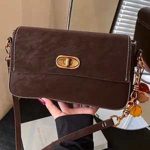 Dunkelbraune Umhängetasche mit Kontrastnähten und Blattanhänger in Vintage-Optik