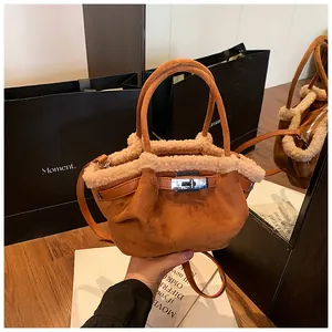Detail of a brown suede mini bucket bag with soft faux fur trim and silver turn-lock closure