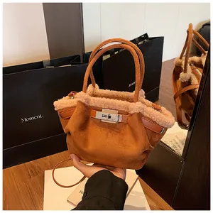 Detail of caramel suede bucket bag with white faux shearling trim and silver metal twist lock