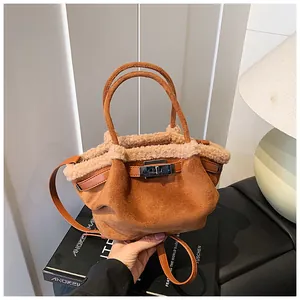 Detailed close-up of brown suede bucket bag with soft beige faux fur trim and silver clasp
