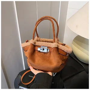Detail of caramel suede bucket bag with beige faux shearling trim and silver metal twist lock
