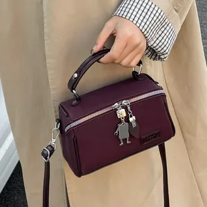 Borsa a mano vintage bordeaux con ciondolo robot e tracolla su cappotto beige neutro