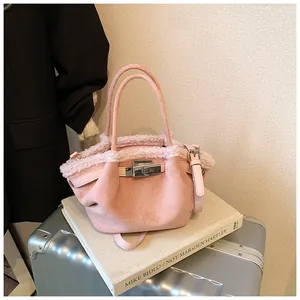 Detailed view of pink suede bucket bag with shearling trim and silver metal clasp