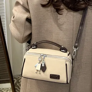 Borsa a scatola beige minimalista con texture a grana e ciondolo robot unico in dettaglio