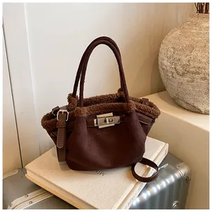 Detail of dark brown suede bucket bag with faux fur trim and silver metallic twist lock