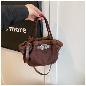 Detail view of dark brown suede bucket bag with plush trim and silver twist lock closure