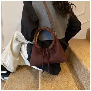 Dettaglio della borsa in pelle scamosciata marrone scuro con manico in shearling e fiocco