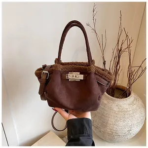 Close-up of dark brown suede bucket bag featuring faux shearling trim and silver metal twist lock
