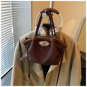 Brown faux suede bucket bag with plush trim and silver twist lock on a display stand