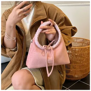 Dettaglio borsa scamosciata rosa con manico in shearling e patch con logo del marchio