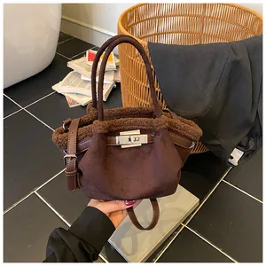 Detail of dark brown suede bucket bag with plush faux fur trim and silver metal twist lock