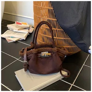 Detail of brown suede bucket bag with teddy fur trim and silver turn-lock closure