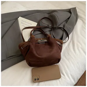 Detail of brown suede bucket bag with shearling trim and silver metal twist lock