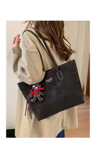 Detail of black tote bag with white contrast stitching and cute teddy bear pendant charm