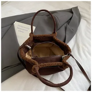 Detail view of brown suede bucket bag with faux fur trim and secure double zipper interior
