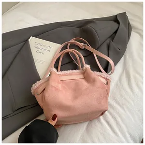 Detail of pink faux suede bucket bag featuring plush faux fur trim and adjustable strap
