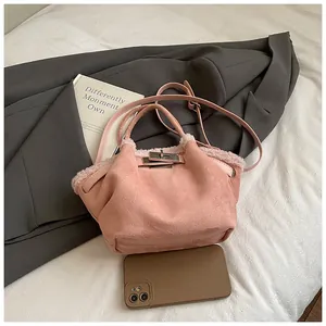 Detail of pink faux suede bucket bag with fur trim, silver clasp and phone for size scale