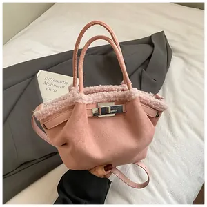 Close-up of pink suede bucket bag with faux shearling trim and silver metal twist lock