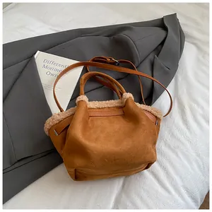 Detailed texture of brown suede bucket bag with soft faux shearling trim and dual handles