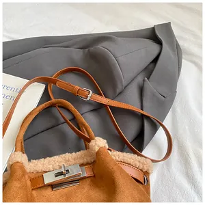 Detail of brown suede bucket bag with white faux fur trim and silver turn-lock closure