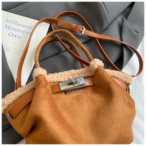 Detail of brown suede bucket bag with faux shearling trim and silver metal lock closure