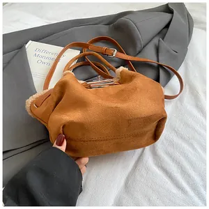 Detail of brown suede bucket bag with beige faux fur trim and silver metal buckle
