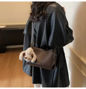 Detail of dark brown lychee textured leather bag with a cute beige bunny plush charm